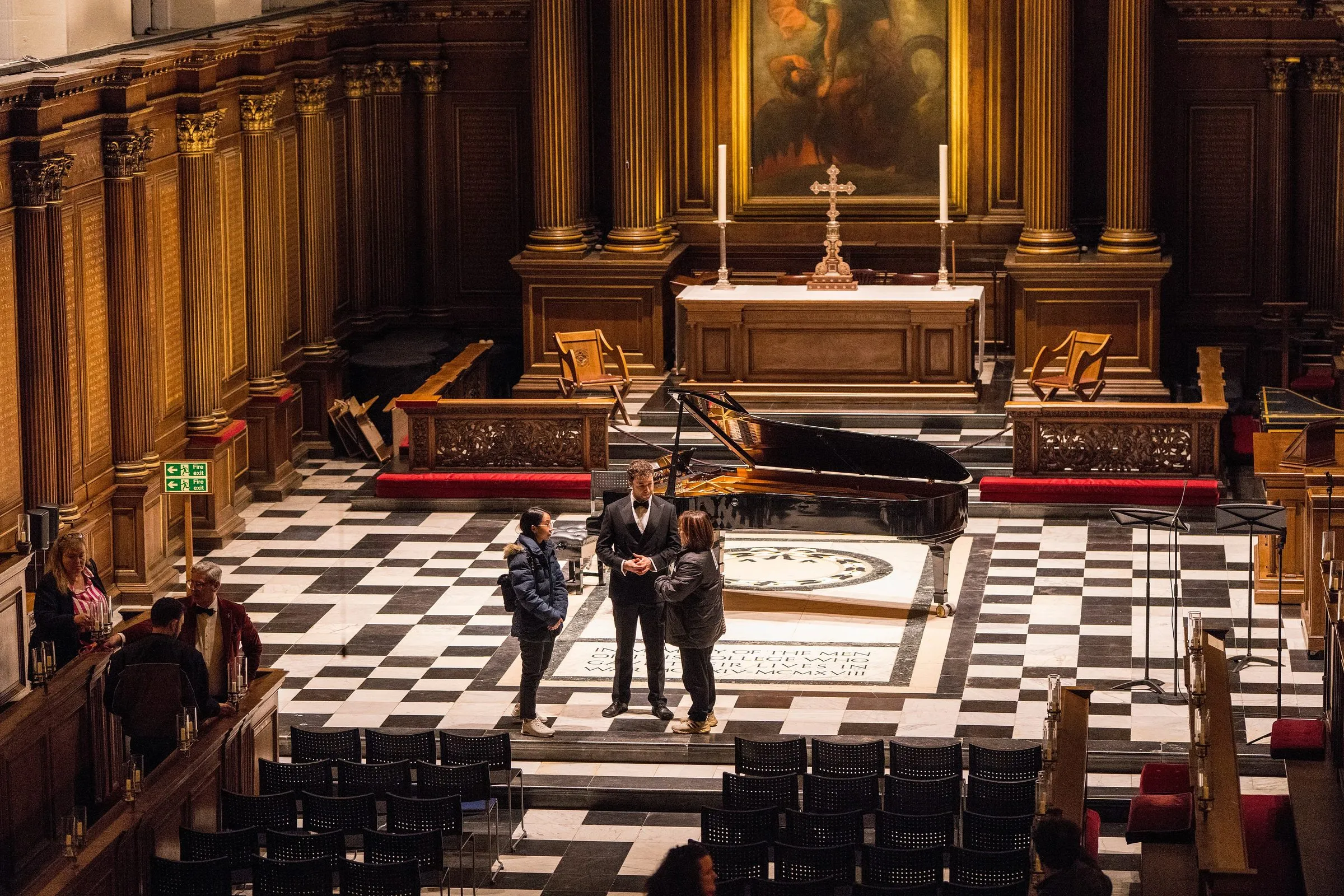 Performers and a grand piano before the altar of Trinity College Chapel, seen from the gallery