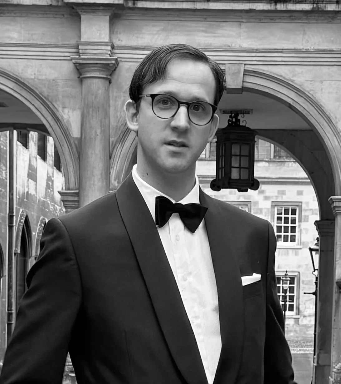 Garth White in black tie beneath a stone college arcade