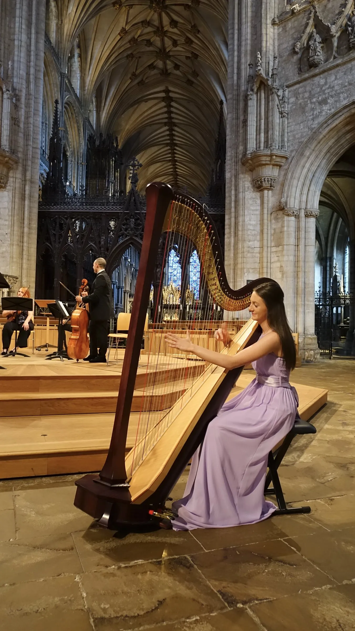 A harpist in a lilac gown performs in the cathedral