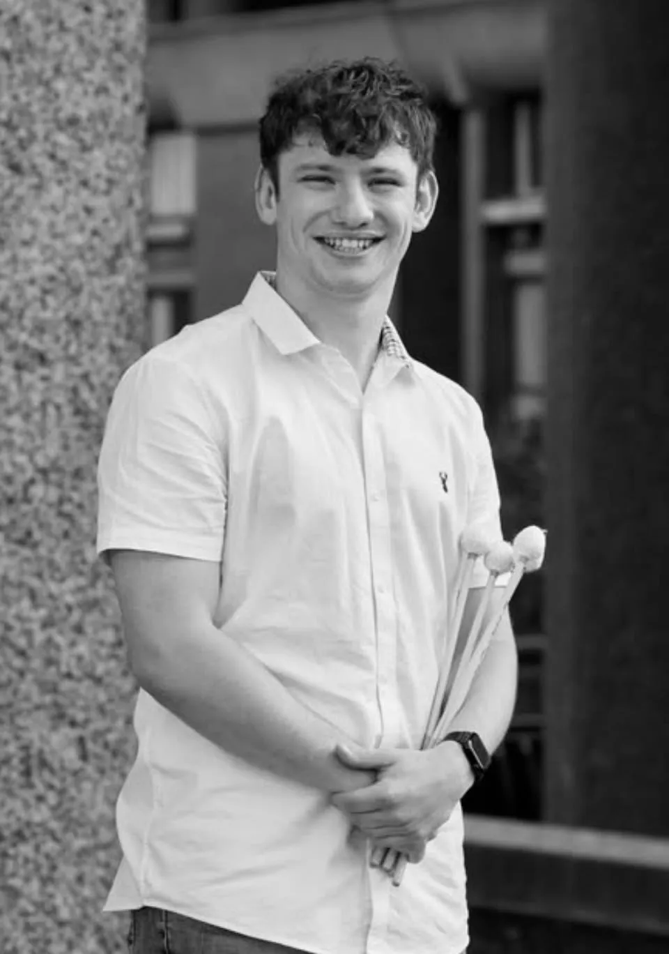 Jordan Ashman smiling, holding his timpani mallets