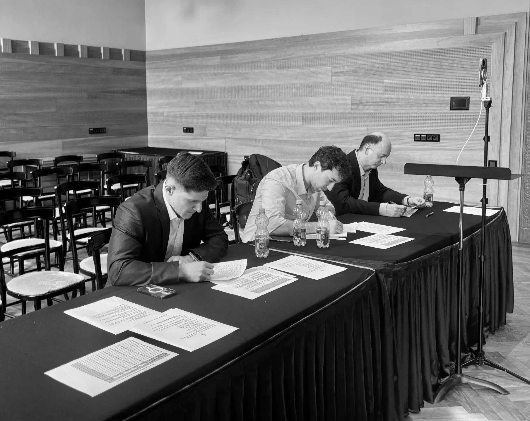 Three judges marking at a blue-draped table during the Series 4 awards at the Liszt Academy
