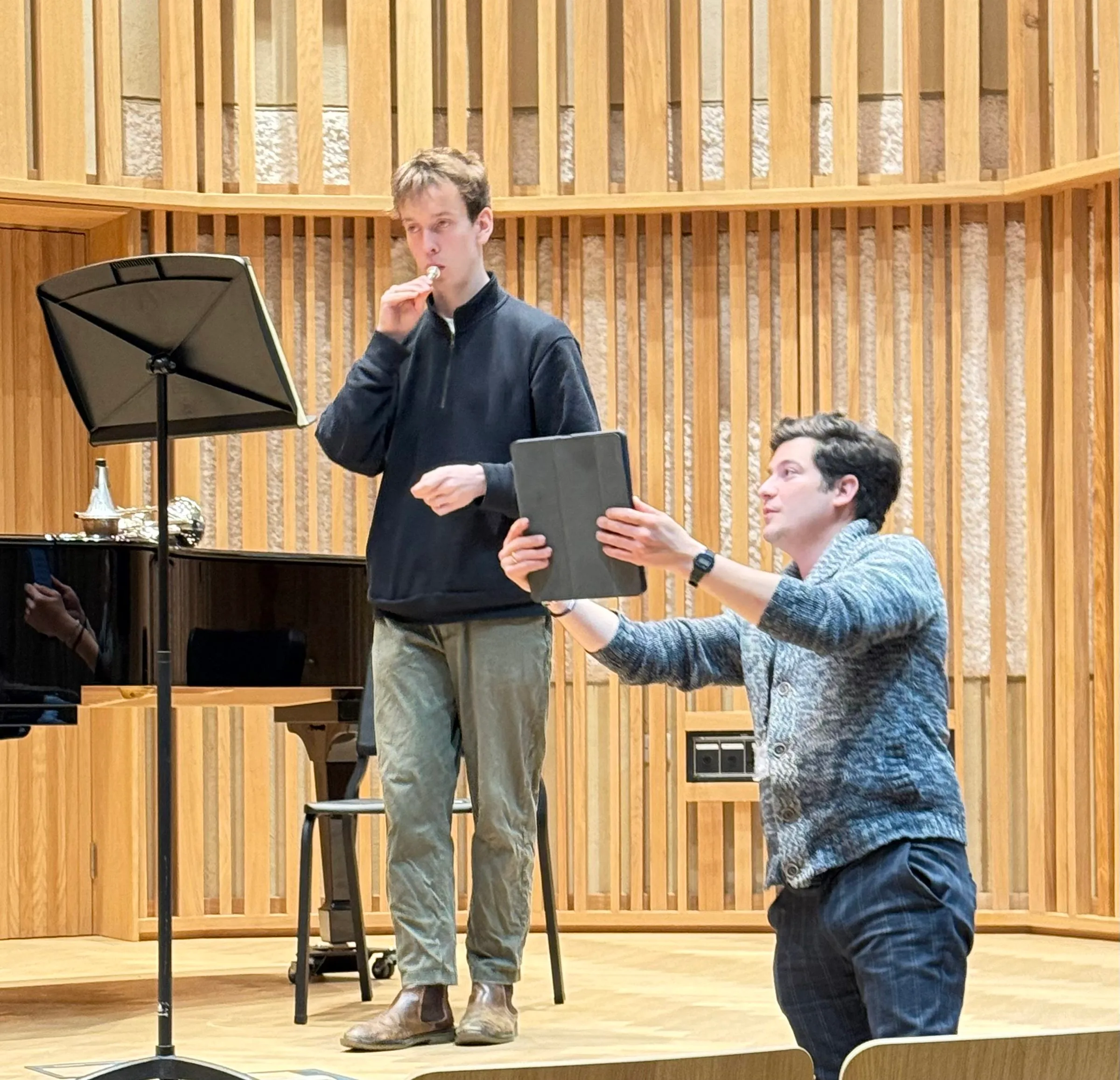 A tutor coaches a musician on stage during the master class