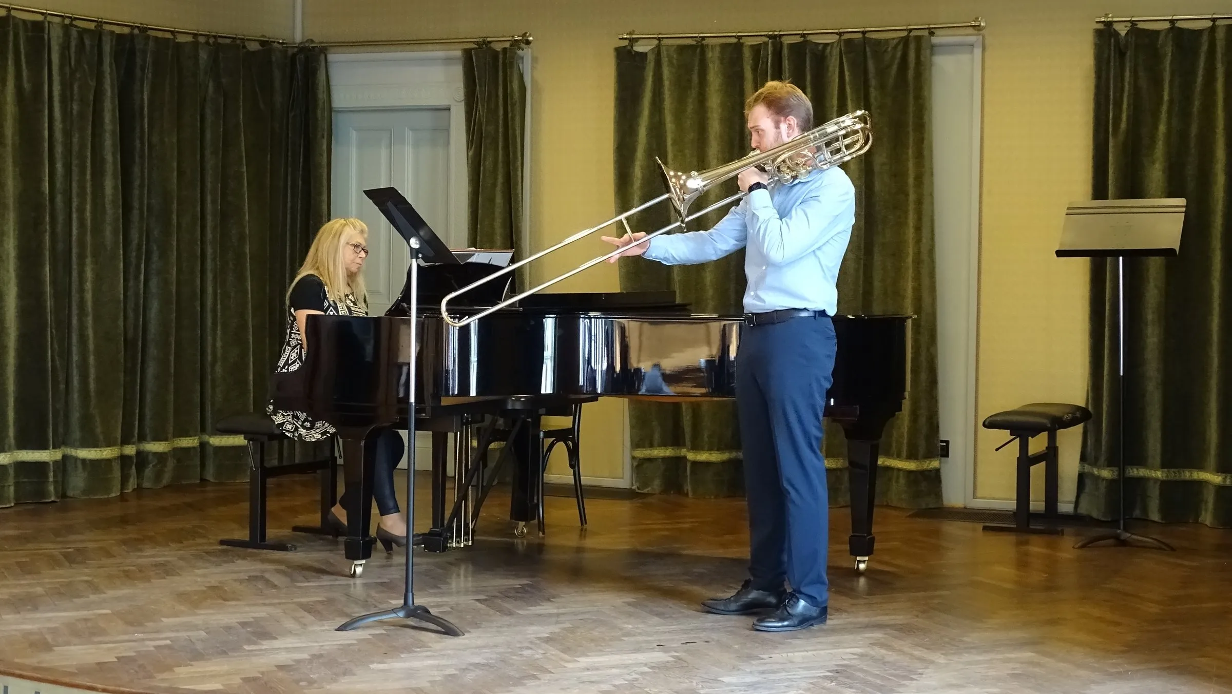 A trombonist and pianist perform on the stage of the competition hall